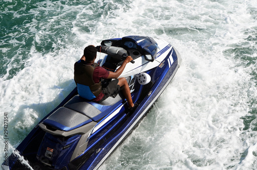 An angled overhead closeup view of a man riding a blue jetski