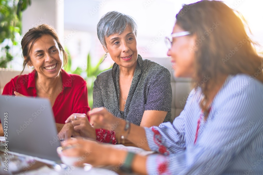 Meeting of middle age women having lunch and drinking coffee. Mature friends smiling happy using laptop at home on a sunny day Meeting of middle age women having lunch and drinking coffee. Mature friends smiling happy using laptop at home on a sunny day