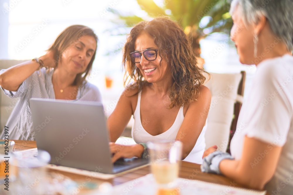 Meeting of middle age women having lunch and drinking coffee. Mature friends smiling happy using laptop at home on a sunny day Meeting of middle age women having lunch and drinking coffee. Mature friends smiling happy using laptop at home on a sunny day