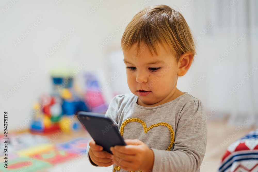 Baby using phone, playing game or watching cartoons. Home indoors. Screen time Baby using phone, playing game or watching cartoons. Home indoors. Screen time