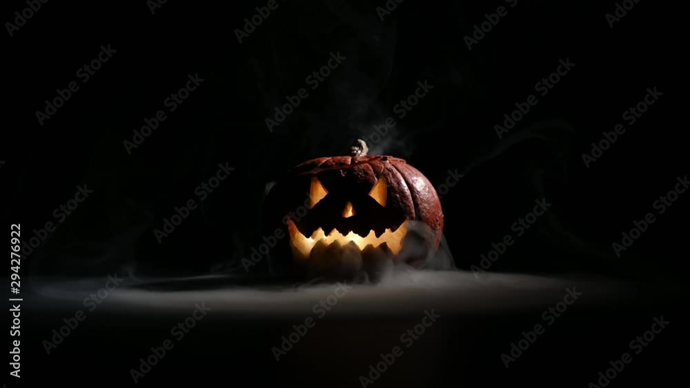 Halloween, orange pumpkin with a scary luminous face on a dark ...