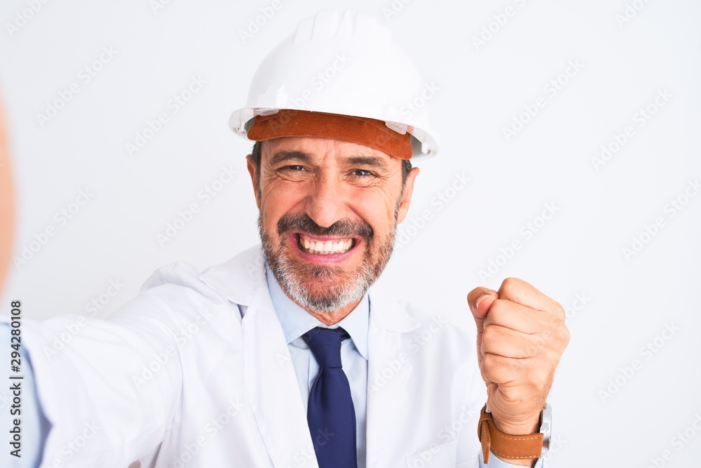 Middle age engineer man wearing helmet make selfie over isolated white background screaming proud and celebrating victory and success very excited, cheering emotion