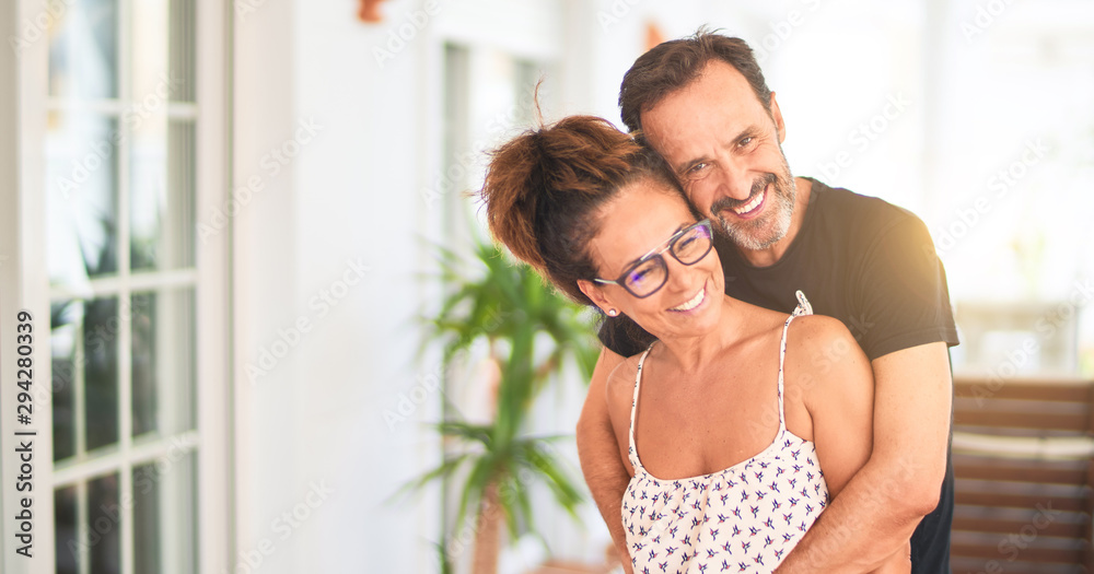 Fototapeta premium Middle age beautiful couple standing on terrace hugging and smiling