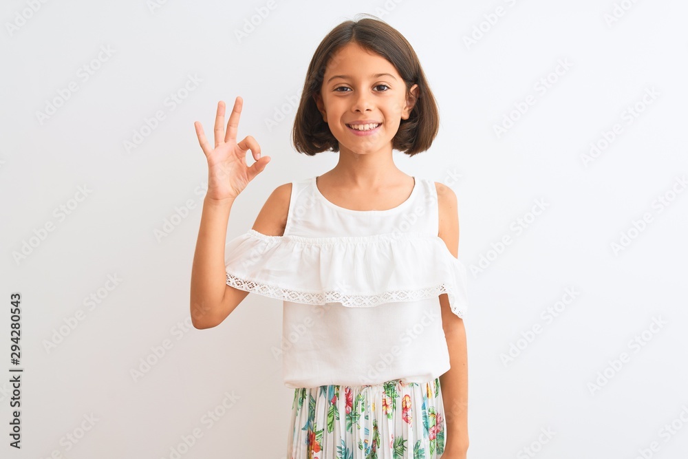 Young beautiful child girl wearing casual dress standing over isolated white background smiling positive doing ok sign with hand and fingers. Successful expression. Young beautiful child girl wearing casual dress standing over isolated white background smiling positive doing ok sign with hand and fingers. Successful expression.