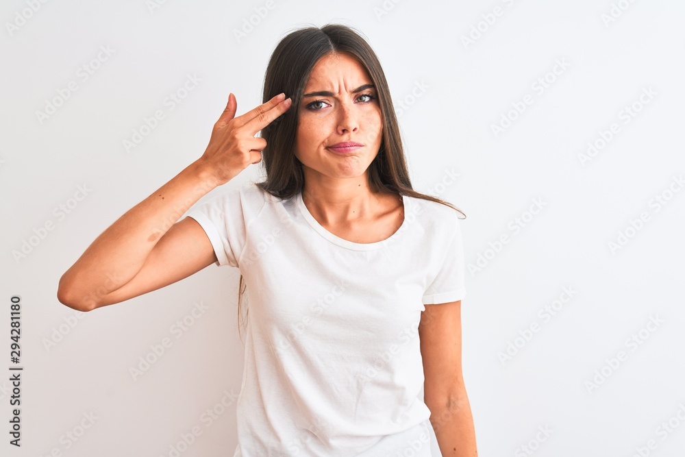 Young beautiful woman wearing casual t-shirt standing over isolated white background Shooting and killing oneself pointing hand and fingers to head like gun, suicide gesture. Young beautiful woman wearing casual t-shirt standing over isolated white background Shooting and killing oneself pointing hand and fingers to head like gun, suicide gesture.