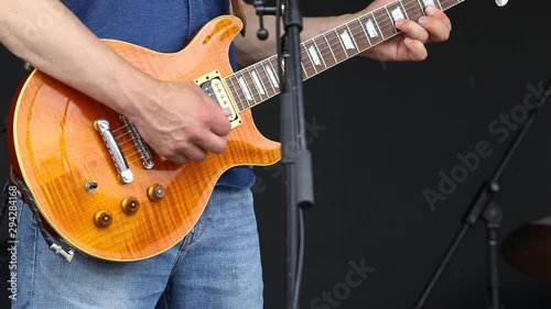 Native band entertain at music festival. A closeup video shot in slow-mo, showing a man playing a guitar on stage during an acoustic music set at a local concert celebrating traditional music.
