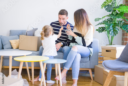 Beautiful family, parents sitting on the sofa drinking coffee looking his kid playing at new home around cardboard boxes © Krakenimages.com