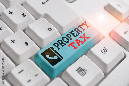 Text sign showing Property Tax. Business photo text an ad valorem tax on the value of a property Millage rate White pc keyboard with empty note paper above white background key copy space photo