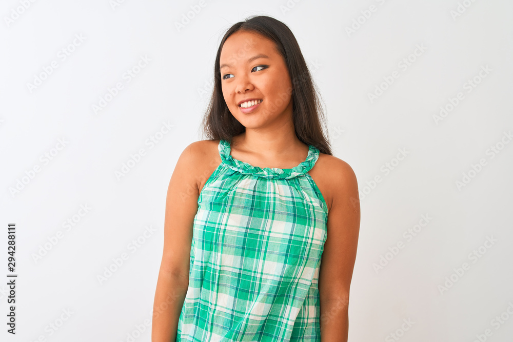 Young chinese woman wearing green dress standing over isolated white background looking away to side with smile on face, natural expression. Laughing confident. Young chinese woman wearing green dress standing over isolated white background looking away to side with smile on face, natural expression. Laughing confident.