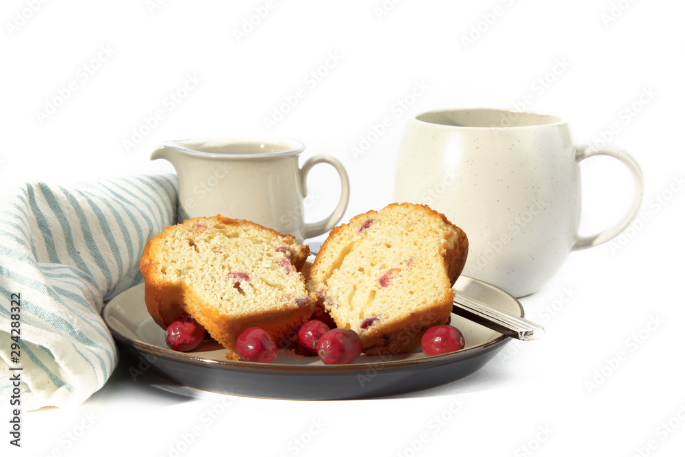 a cranberry lemon muffin cut in half on a plate with a coffee cup with a green napkin isolated on white a cranberry lemon muffin cut in half on a plate with a coffee cup with a green napkin isolated on white