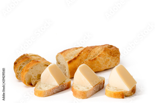 crusty French stick bread cut into slices topped with smoked Gouda cheese wedges isolated on white