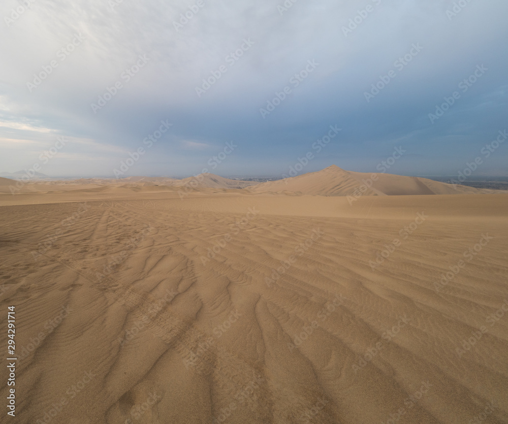 tire tracks over the sand at Ica desert, dunes in the horizon