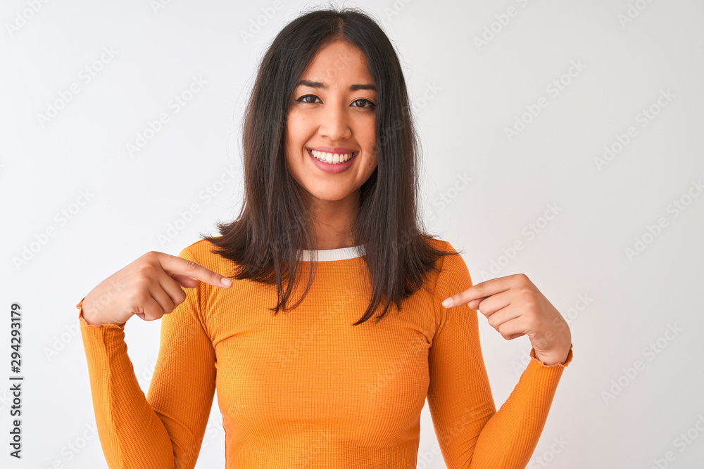 Young beautiful chinese woman wearing orange t-shirt standing over isolated white background looking confident with smile on face, pointing oneself with fingers proud and happy. Young beautiful chinese woman wearing orange t-shirt standing over isolated white background looking confident with smile on face, pointing oneself with fingers proud and happy.