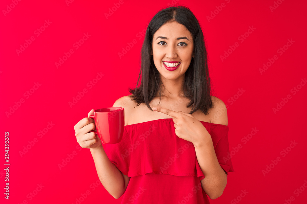 Young beautiful chinese woman drinking cup of coffee standing over isolated red background very happy pointing with hand and finger Young beautiful chinese woman drinking cup of coffee standing over isolated red background very happy pointing with hand and finger
