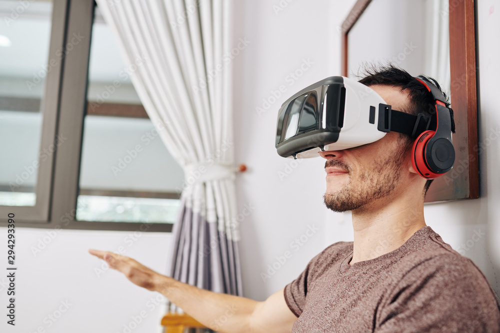 © DragonImages - Positive young man wearing VR headset when testing new application he created