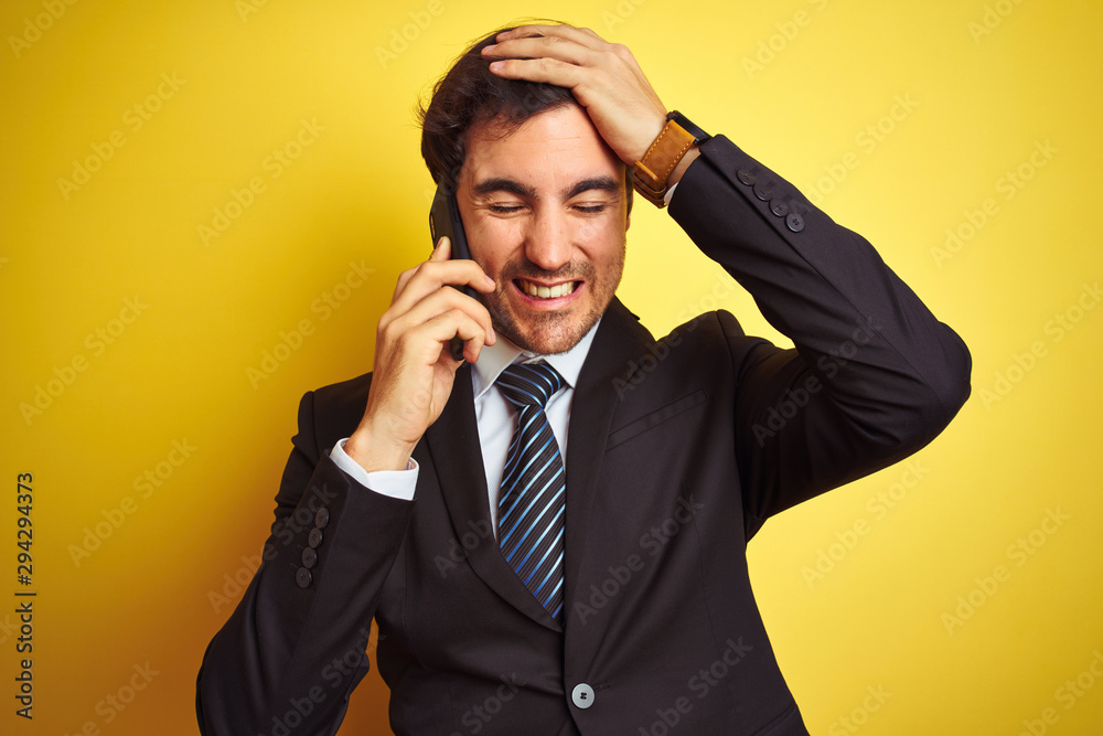 Young handsome businessman talking on the smartphone over isolated yellow background stressed with hand on head, shocked with shame and surprise face, angry and frustrated. Fear and upset for mistake. Young handsome businessman talking on the smartphone over isolated yellow background stressed with hand on head, shocked with shame and surprise face, angry and frustrated. Fear and upset for mistake.