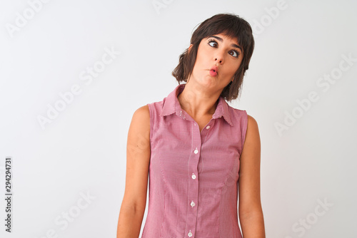 Young beautiful woman wearing red summer shirt standing over isolated white background making fish face with lips, crazy and comical gesture. Funny expression.