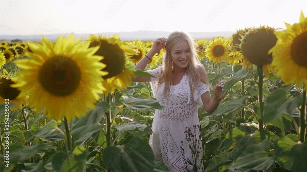 Young woman in a hat flirts and smiles near sunflowers. Portrait view. Young woman in a hat flirts and smiles near sunflowers. Portrait view.