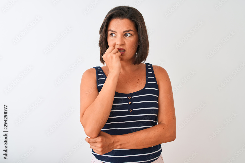 Young beautiful woman wearing blue striped t-shirt standing over isolated white background looking stressed and nervous with hands on mouth biting nails. Anxiety problem. Young beautiful woman wearing blue striped t-shirt standing over isolated white background looking stressed and nervous with hands on mouth biting nails. Anxiety problem.