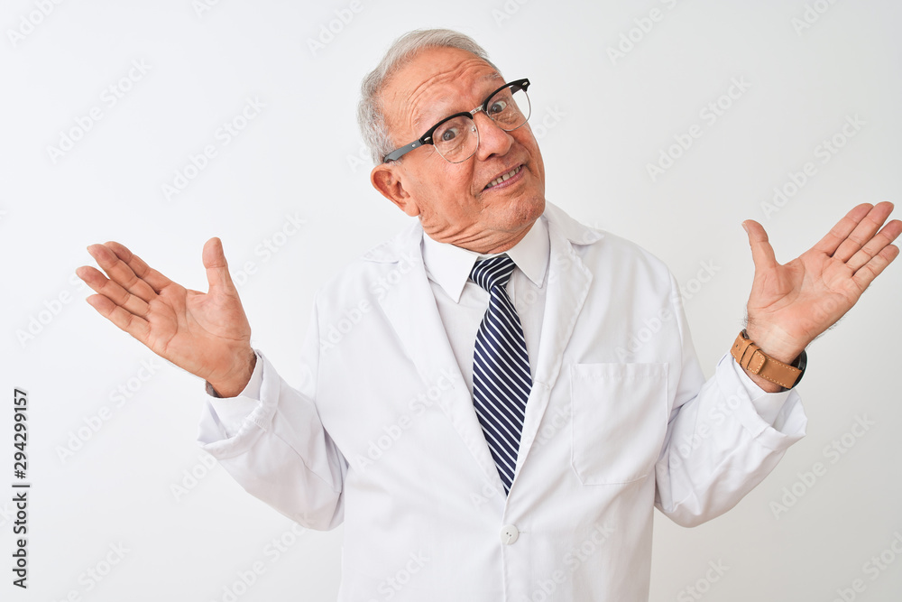 Senior grey-haired scientist man wearing coat standing over isolated white background clueless and confused expression with arms and hands raised. Doubt concept. Senior grey-haired scientist man wearing coat standing over isolated white background clueless and confused expression with arms and hands raised. Doubt concept.