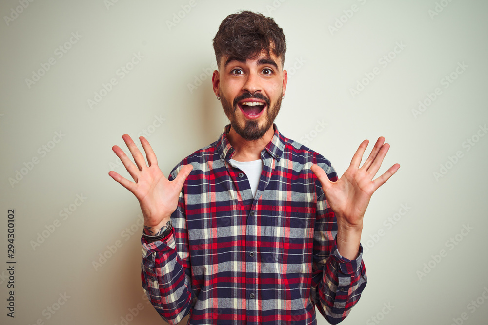 Young man wearing casual shirt standing over isolated white background celebrating crazy and amazed for success with arms raised and open eyes screaming excited. Winner concept Young man wearing casual shirt standing over isolated white background celebrating crazy and amazed for success with arms raised and open eyes screaming excited. Winner concept
