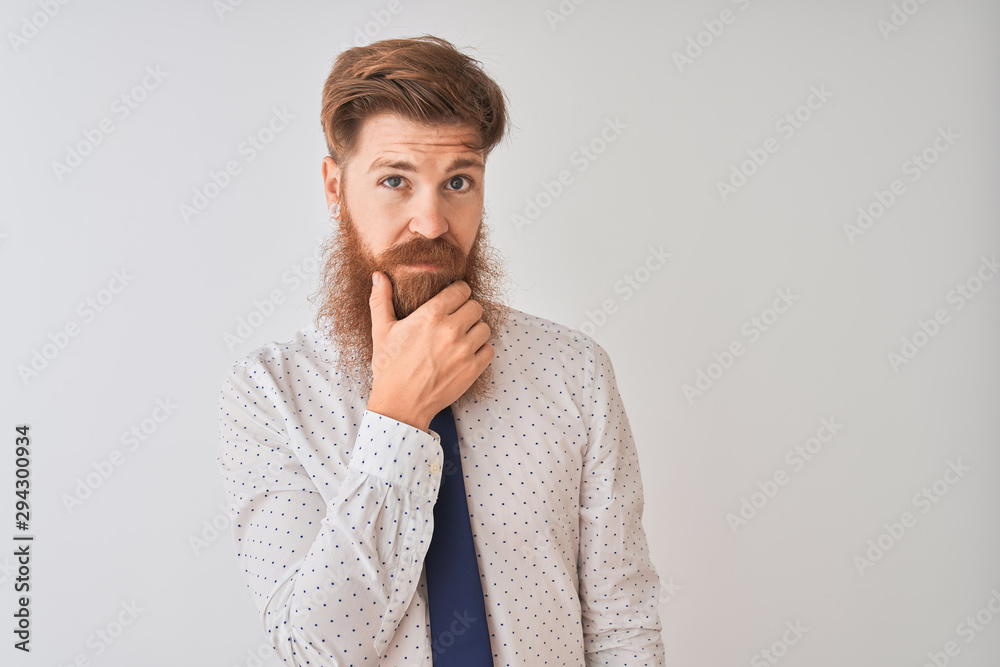 Young redhead irish businessman standing over isolated white background looking confident at the camera smiling with crossed arms and hand raised on chin. Thinking positive. Young redhead irish businessman standing over isolated white background looking confident at the camera smiling with crossed arms and hand raised on chin. Thinking positive.