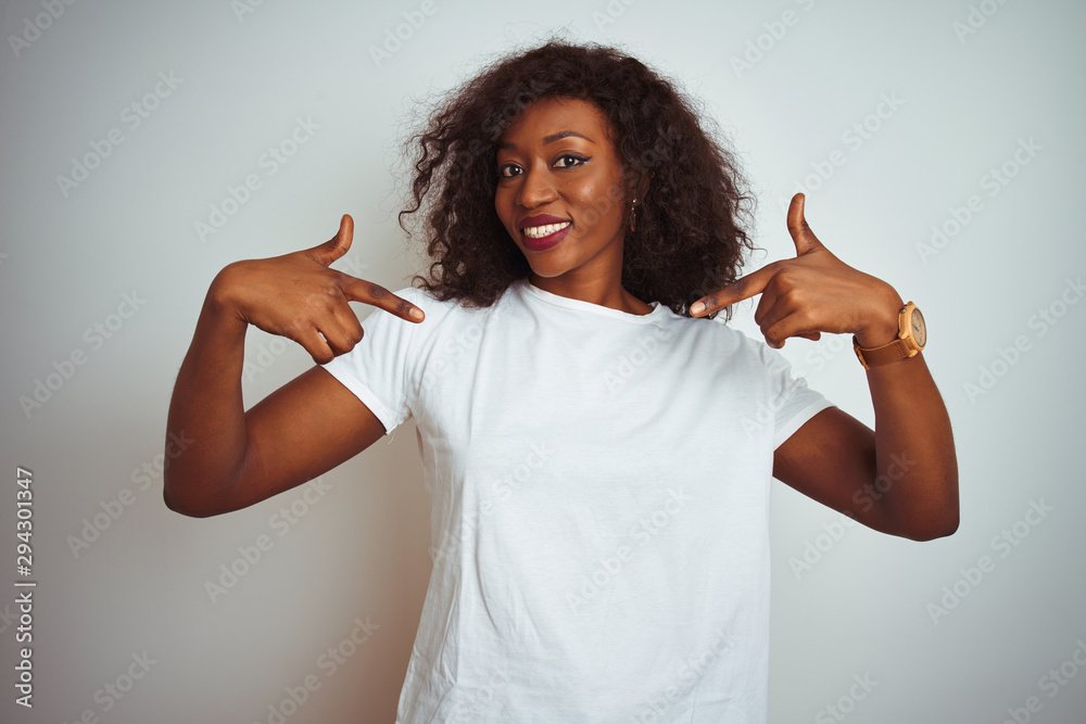 Young african american woman wearing t-shirt standing over isolated white background looking confident with smile on face, pointing oneself with fingers proud and happy. Young african american woman wearing t-shirt standing over isolated white background looking confident with smile on face, pointing oneself with fingers proud and happy.