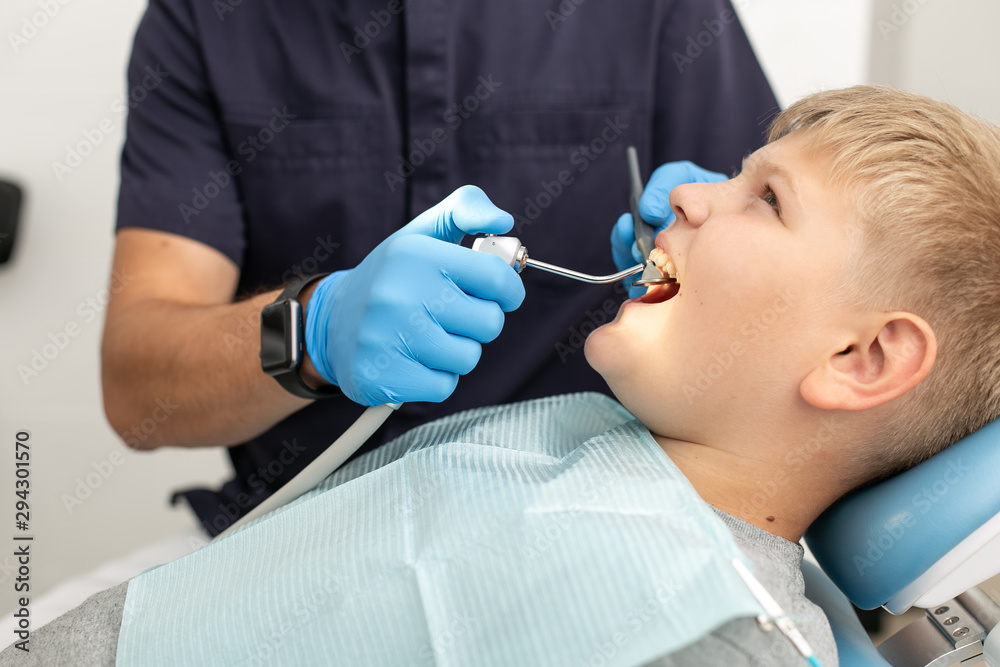 Young boy hold his mouth open while his doctor mothwashing it Young boy hold his mouth open while his doctor mothwashing it