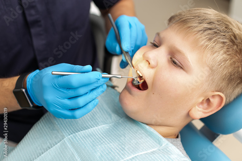 Fototapeta Naklejka Na Ścianę i Meble -  Closeup of young boy lying on the dental chair and is being examinated by a doctor