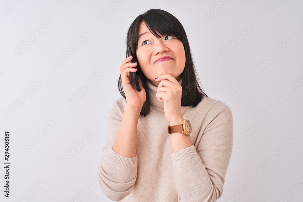 Young beautiful Chinese woman talking on the smartphone over isolated white background serious face thinking about question, very confused idea Young beautiful Chinese woman talking on the smartphone over isolated white background serious face thinking about question, very confused idea