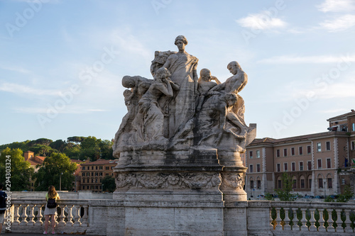 Marble composition on the bridge of Victor Emmanuel II over the Tiber River in Rome, symbolizing freedom and unity.