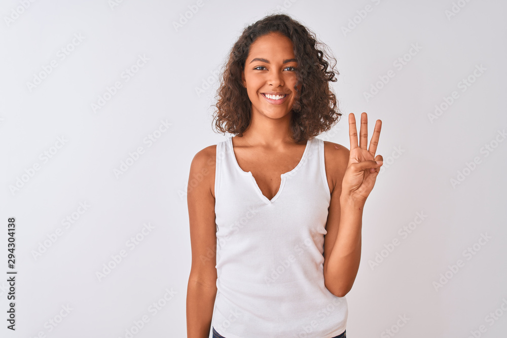 Young brazilian woman wearing casual t-shirt standing over isolated white background showing and pointing up with fingers number three while smiling confident and happy. Young brazilian woman wearing casual t-shirt standing over isolated white background showing and pointing up with fingers number three while smiling confident and happy.
