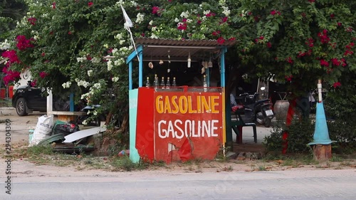 Motorbikes driving past vintage gasoline stand with glass bottles on Koh Phangan, Thailand. photo