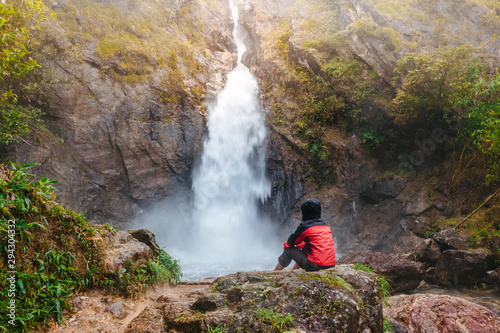 asian women sitting on the rock and watching water fall on holiday