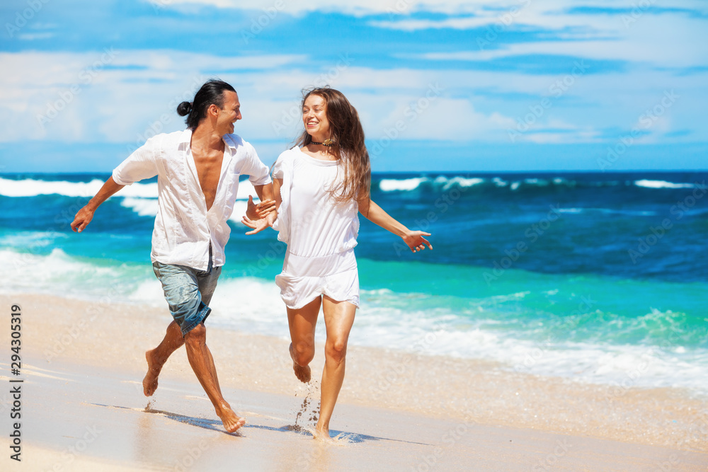 Happy family on honeymoon holiday - just married young couple having fun, run by water edge along sea beach surf. Active lifestyle, people recreational activity on summer vacation on tropical island. Happy family on honeymoon holiday - just married young couple having fun, run by water edge along sea beach surf. Active lifestyle, people recreational activity on summer vacation on tropical island.