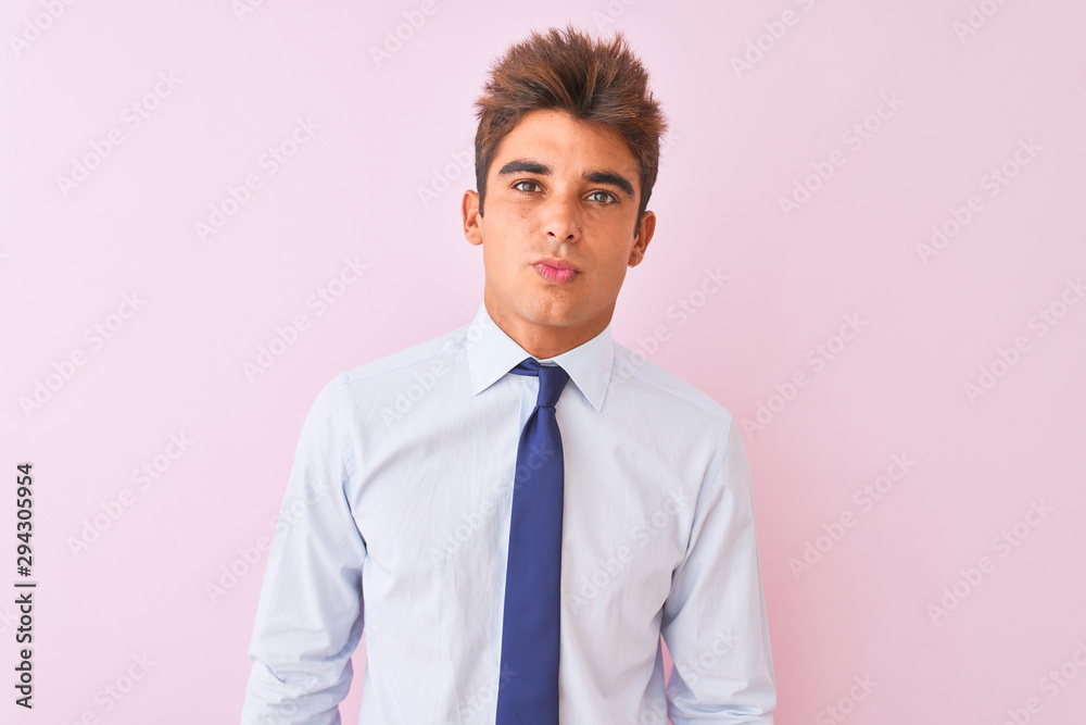 Young handsome businessman wearing shirt and tie standing over isolated pink background looking at the camera blowing a kiss on air being lovely and sexy. Love expression.