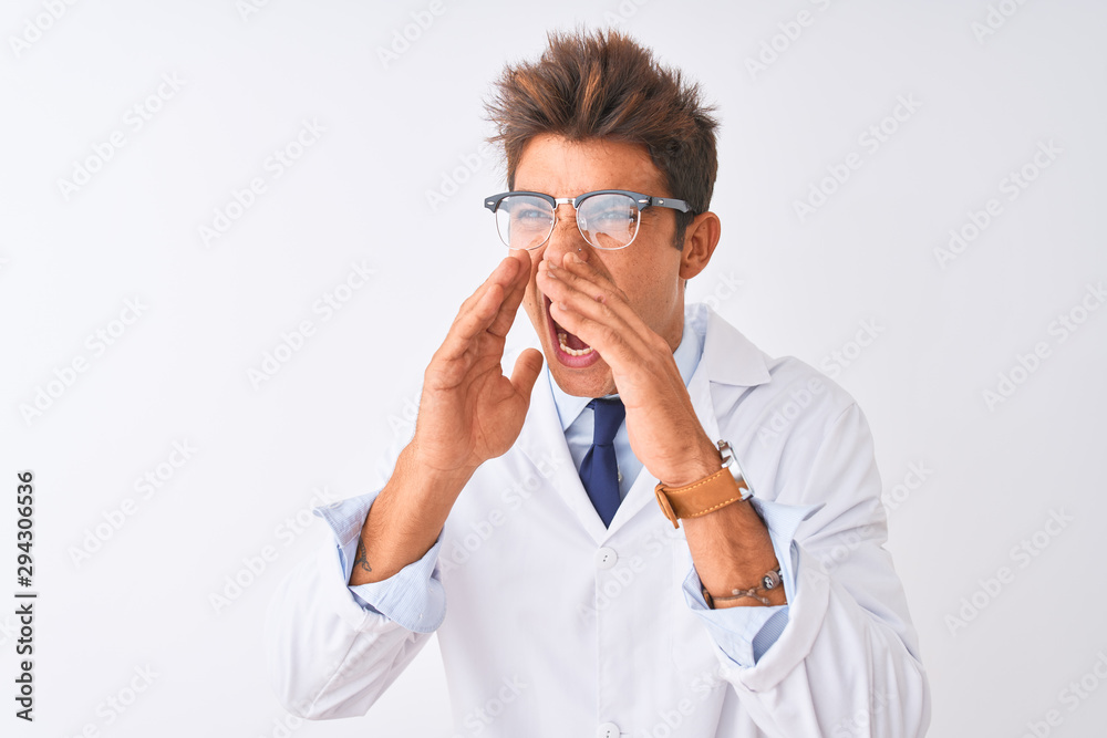 Young handsome sciencist man wearing glasses and coat over isolated white background Shouting angry out loud with hands over mouth Young handsome sciencist man wearing glasses and coat over isolated white background Shouting angry out loud with hands over mouth