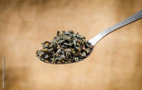 spoon with aromatic black tea and green tea leaves on a traditional background