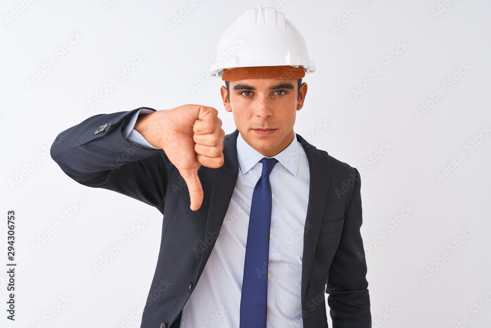 Young handsome architect man wearing suit and helmet over isolated white background looking unhappy and angry showing rejection and negative with thumbs down gesture. Bad expression.