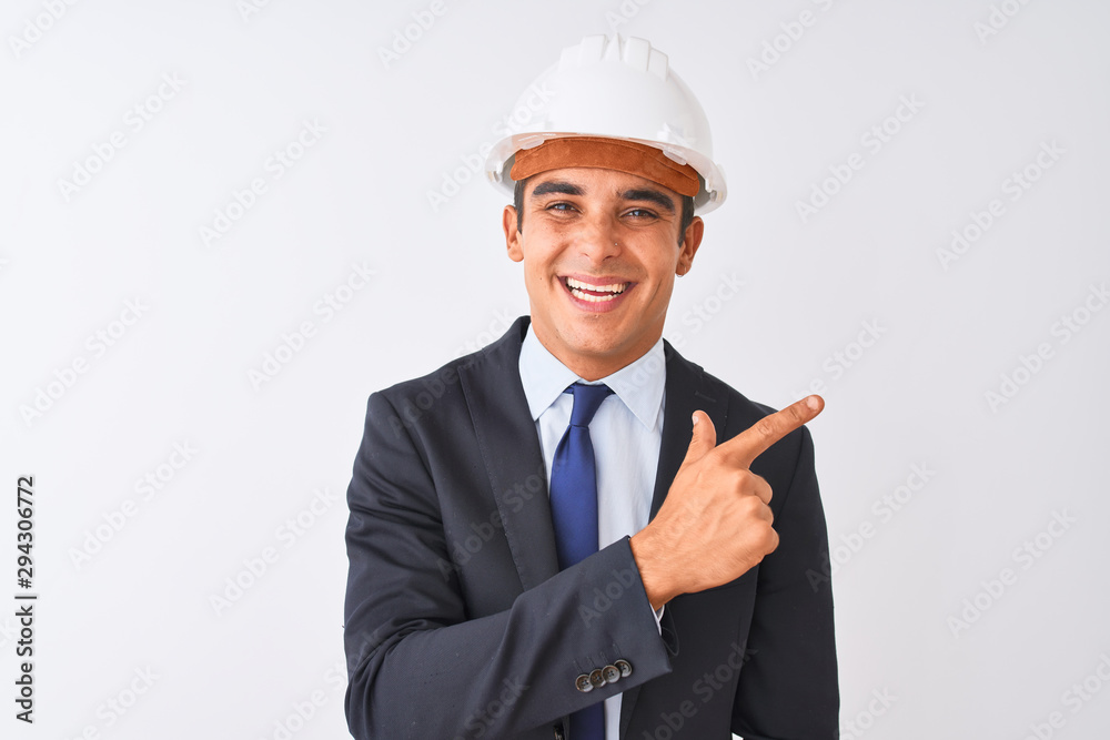 Young handsome architect man wearing suit and helmet over isolated white background cheerful with a smile of face pointing with hand and finger up to the side with happy and natural expression on face