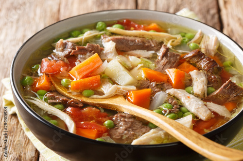 Thick slowly cooked soup with vegetables and meat close-up in a plate. horizontal