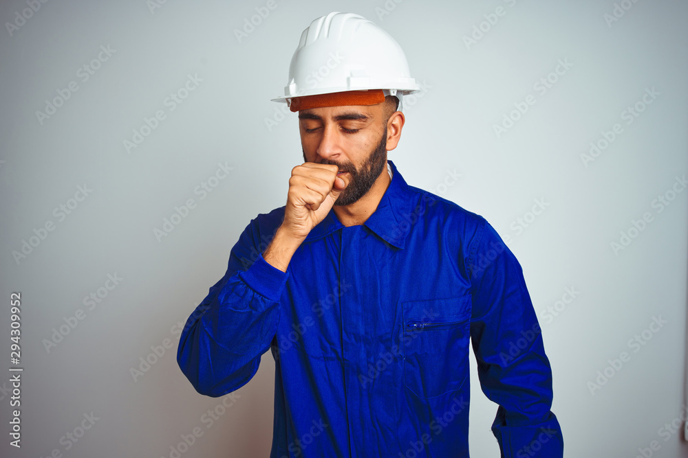 Handsome indian worker man wearing uniform and helmet over isolated white background feeling unwell and coughing as symptom for cold or bronchitis. Healthcare concept.