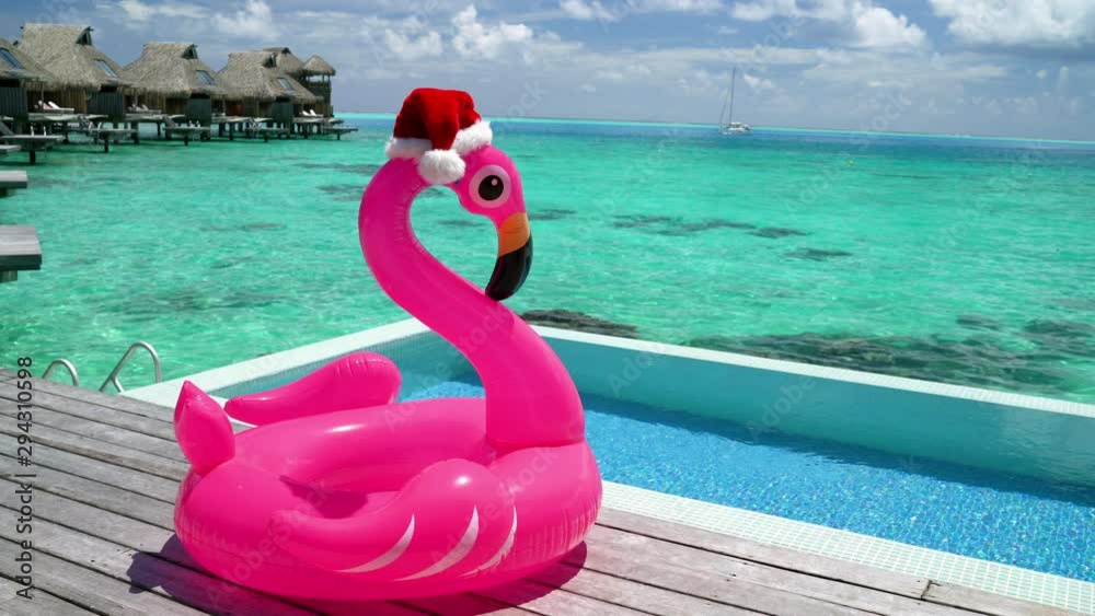Christmas beach vacation flamingo pool float with santa hat travel background for winter holidays luxury getaway holiday.
