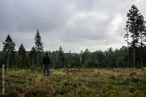 Pensive young man standing in czech forest with dark mood dramatic sky © Space Creator