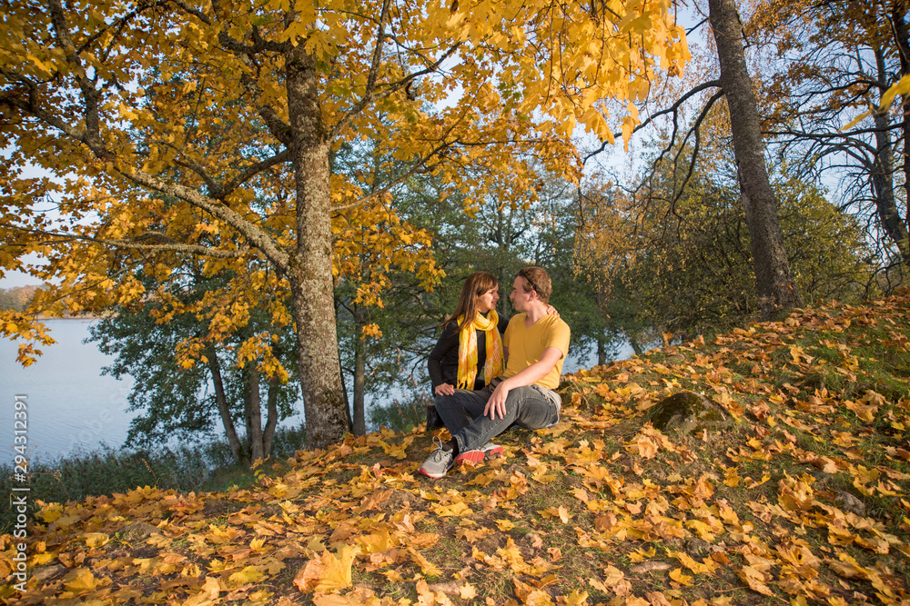 Young couple on lake coast. Sunny Autumn Day. Young couple on lake coast. Sunny Autumn Day.