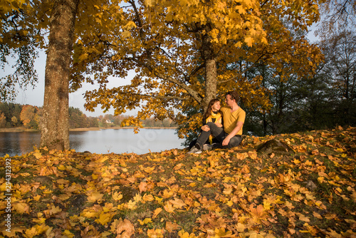 Young couple on lake coast. Sunny Autumn Day.