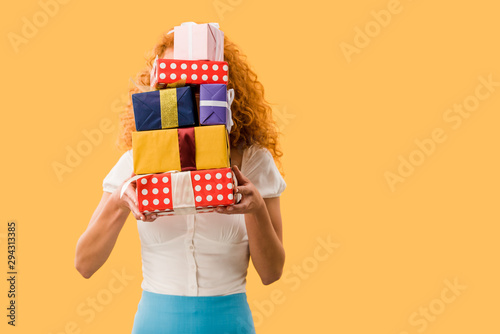 young woman holding gifts isolated on yellow © LIGHTFIELD STUDIOS
