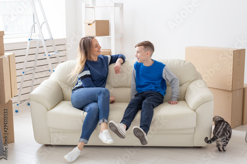 Satisfied happy caucasian single mother and son happily communicate discussing the design of the new apartment during the housewarming party with their scottish fold cat.