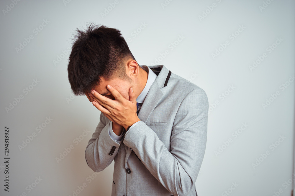 Asian chinese businessman wearing suit and tie standing over isolated yellow background with sad expression covering face with hands while crying. Depression concept. Asian chinese businessman wearing suit and tie standing over isolated yellow background with sad expression covering face with hands while crying. Depression concept.