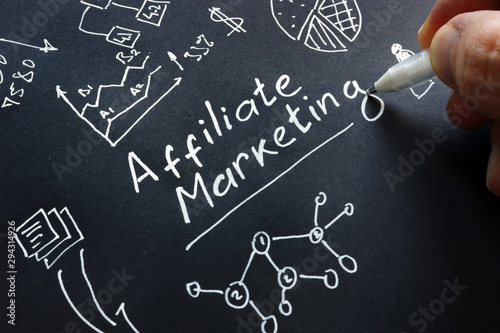 Man is writing Affiliate marketing on a black surface. photo